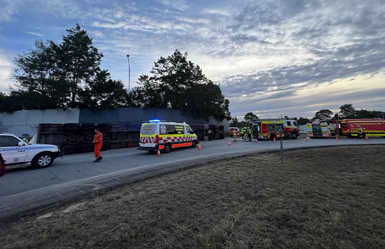 The B-double tipped on its side at the John Oxley Drive and Oxley Highway roundabout. Photos: supplied by @PortMacquarieOnScene.