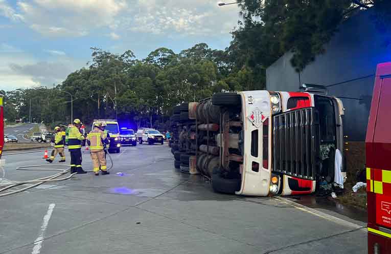 The B-double tipped on its side at the John Oxley Drive and Oxley Highway roundabout. Photos: supplied by @PortMacquarieOnScene.